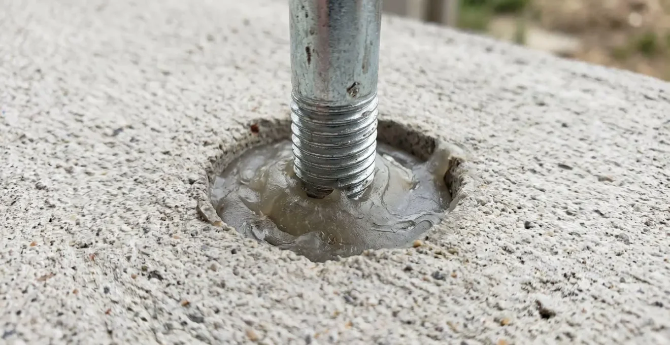 Gros plan sur une cheville chimique avec résine époxy visible dans un trou percé dans du béton